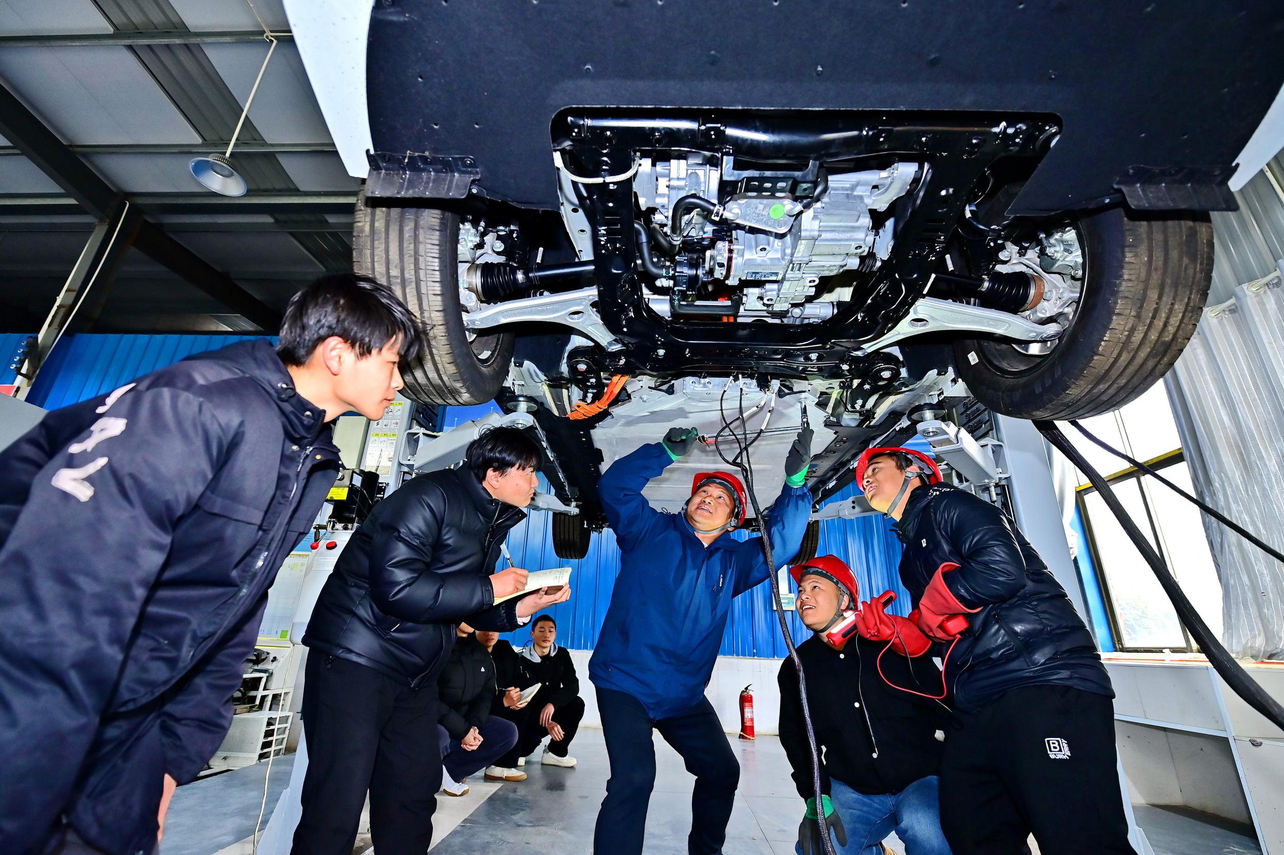 2025年2月，江西省宜春市，丰城市的一所技工学校实训基地内，新能源汽车运维专业学生在老师的指导下学习新能源汽车电池包检修技术。